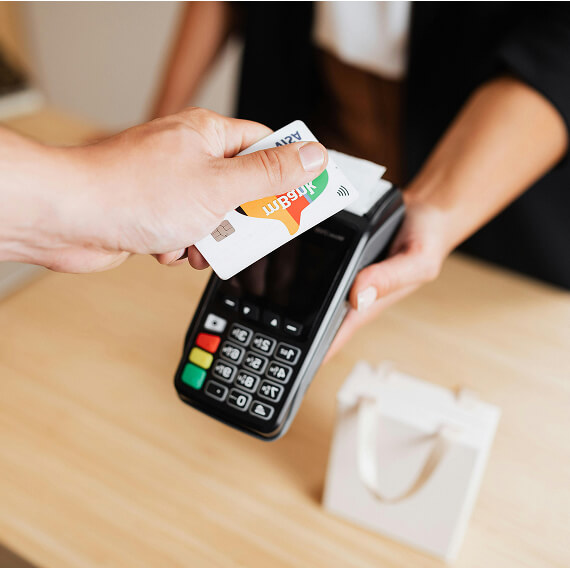 Une personne tient une carte de paiement au-dessus d&apos;un terminal de paiement de DNA Soft Solution.